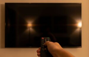 Mondiali su DAZN: lo schermo della smart TV si spegne da solo, ecco perché Telecomando puntato verso uno schermo di smart TV completamente nero e spento in un salotto, durante la visione di una partita dei Mondiali 2026 su DAZN