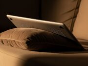 Il laptop sul divano d’estate: la presa d’aria bloccata che accumula danni invisibili sulla scheda madre Laptop appoggiato su cuscino di divano con griglie di ventilazione ostruite dal tessuto morbido