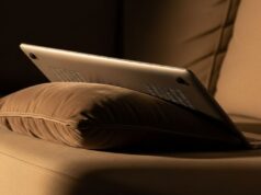 Il laptop sul divano d’estate: la presa d’aria bloccata che accumula danni invisibili sulla scheda madre Laptop appoggiato su cuscino di divano con griglie di ventilazione ostruite dal tessuto morbido