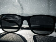 Occhiali da sole in auto col caldo: l’errore che spacca il trattamento dall’interno Occhiali da sole con lente craquelé sul cruscotto dell'auto al sole