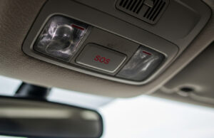 La chiamata di emergenza dell’auto può spegnersi in estate: come controllare il pulsante SOS Pulsante SOS rosso sulla plafoniera di un'auto moderna ripreso dal sedile del conducente, sistema eCall per la chiamata di emergenza automatica