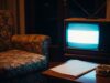 Drive In, il programma degli anni ’80 che cambiò la domenica sera italiana per sempre Televisore CRT anni '80 acceso in un salotto italiano buio con poltrona a fiori e posacenere sul tavolino