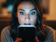 Le foto che cancelli dal telefono non sono sparite: chi può ancora vederle Donna sorpresa mentre guarda lo schermo di uno smartphone acceso al buio, illuminata dal bagliore del display
