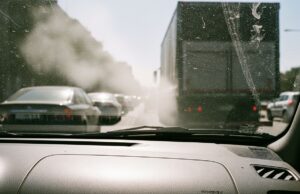 Finestrini aperti in coda: il vero costo non è il carburante, è quello che respiri Traffico congestionato visto dall'abitacolo di un'auto con smog visibile sulla strada