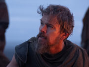 Odissea di Nolan: il segreto tecnico che ha reso possibile girare tutto in IMAX Matt Damon con barba e abiti di scena logori interpreta Ulisse, con il volto illuminato dal bagliore di un fuoco nel film Odissea di Christopher Nolan.
