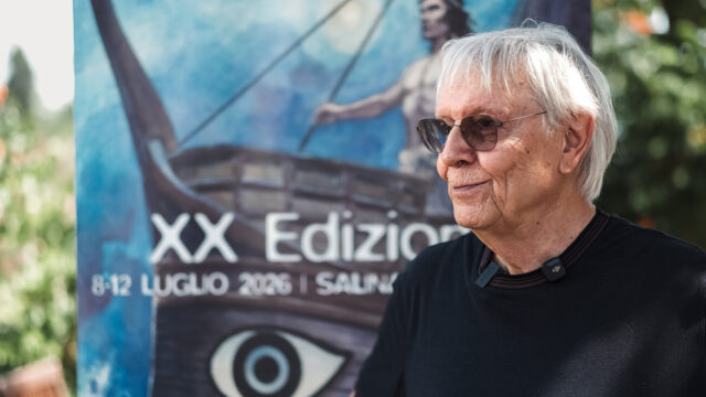 Milo Manara e la sua Odissea disegnata al SalinaDocFest Milo Manara al SalinaDocFest 2026 davanti al poster dell'Odissea, XX edizione del festival a Salina