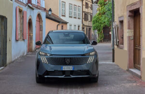 Peugeot E-3008 Long Range: quanto costa davvero un viaggio di 700 km in elettrico Peugeot E-3008 Long Range grigia in un borgo dell'Alsazia durante un viaggio in elettrico a lunga autonomia