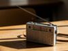 La radiolina nascosta sotto il banco: così si seguivano i Mondiali prima di DAZN Radiolina portatile vintage a transistor con antenna estesa appoggiata su un banco di scuola in legno ruvido.