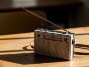 La radiolina nascosta sotto il banco: così si seguivano i Mondiali prima di DAZN Radiolina portatile vintage a transistor con antenna estesa appoggiata su un banco di scuola in legno ruvido.