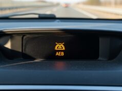 Frenata fantasma in autostrada: perché l’auto frena da sola e cosa fare se capita Spia luminosa del sistema di frenata automatica di emergenza sul cruscotto di un'automobile.