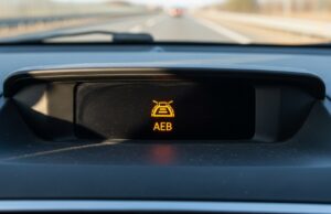 Frenata fantasma in autostrada: perché l’auto frena da sola e cosa fare se capita Spia luminosa del sistema di frenata automatica di emergenza sul cruscotto di un'automobile.