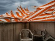 Temporali dopo il caldo: l’errore con tenda da sole e ombrellone che nessuno nota in tempo Tenda da sole a righe arancioni strappata dal vento forte durante un temporale estivo