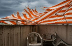 Temporali dopo il caldo: l’errore con tenda da sole e ombrellone che nessuno nota in tempo Tenda da sole a righe arancioni strappata dal vento forte durante un temporale estivo