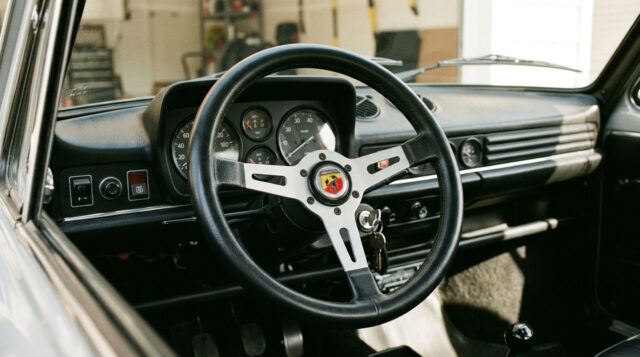 Autobianchi A112 Abarth: il volante che sfidò la Mini Cooper Volante sportivo a tre razze e cruscotto vintage nell'abitacolo di un'utilitaria italiana anni '70, dettaglio ispirato all'Autobianchi A112 Abarth