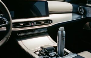 Deodorante spray in auto d’estate: il punto esatto in cui la bomboletta può esplodere Bomboletta spray metallica appoggiata nel vano portaoggetti dell'auto, esposta al calore dell'abitacolo