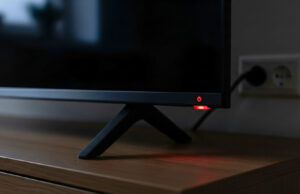 La smart TV in stand-by continua a consumare corrente: quanto costa lasciarla così ogni sera Dettaglio del led rosso acceso su una smart tv spenta in salotto.
