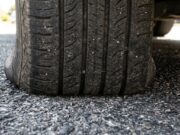 Vibrazioni al volante al rientro dalle vacanze: il vero motivo delle gomme ovalizzate Primo piano del battistrada di un pneumatico appoggiato sull'asfalto, dettaglio della zona di contatto a terra dopo una lunga sosta