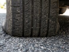 Vibrazioni al volante al rientro dalle vacanze: il vero motivo delle gomme ovalizzate Primo piano del battistrada di un pneumatico appoggiato sull'asfalto, dettaglio della zona di contatto a terra dopo una lunga sosta