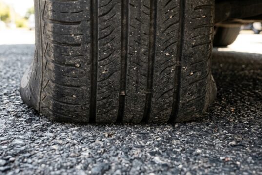 Vibrazioni al volante al rientro dalle vacanze: il vero motivo delle gomme ovalizzate Primo piano del battistrada di un pneumatico appoggiato sull'asfalto, dettaglio della zona di contatto a terra dopo una lunga sosta