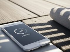 In spiaggia hai le tacche piene ma internet non parte: ecco perché succede davvero Smartphone su passerella di legno con schermo nero e icona di caricamento lento per problemi di rete.