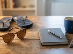 Sindrome da rientro: la statistica del 35% che gira da anni è una bufala Occhiali da sole con sabbia e infradito accanto ad agenda, penna, tazza di caffè e orologio su scrivania in legno, simbolo del passaggio dalle vacanze al rientro