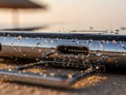 Fotocamera dello smartphone appannata al mare: il gesto che rovina la tenuta stagna Vano SIM e porta USB-C di uno smartphone con sabbia e gocce d'acqua incastrate nella guarnizione, spiaggia al tramonto