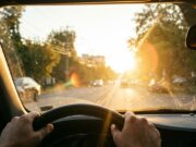Il sole di settembre torna ad abbagliare chi guida: ecco le fasce orarie a rischio Vista dall'abitacolo di un'auto con il sole basso di settembre che abbaglia il parabrezza durante la guida mattutina