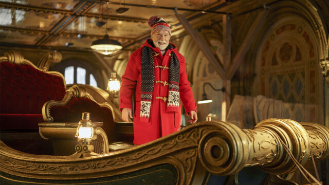 Arnold Schwarzenegger è Babbo Natale in Missione: salvare il Natale Arnold Schwarzenegger è Babbo Natale in cappotto rosso accanto alla slitta dorata, in Missione: salvare il Natale