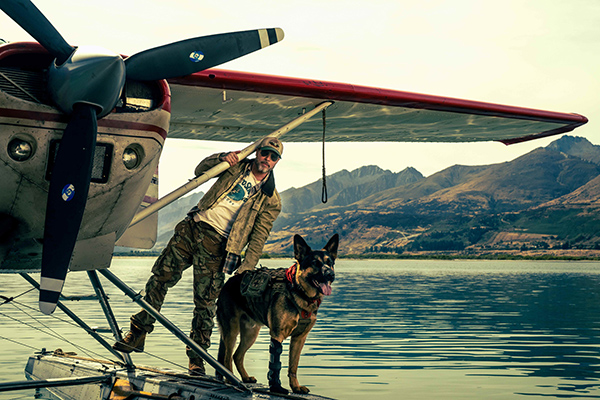 Brad Pitt con il cane pastore tedesco Odino accanto all'idrovolante in Heart of the Beast