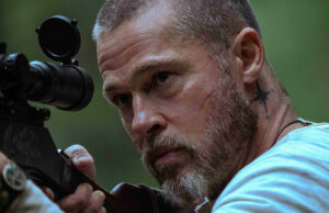Heart of the Beast: perché il cane di Brad Pitt ha una protesi e denti di titanio Primo piano di Brad Pitt con fucile da cecchino in una scena di Heart of the Beast