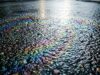 Perché i primi minuti di pioggia sono più pericolosi di un vero temporale Pellicola oleosa iridescente sull'asfalto bagnato nei primi minuti di pioggia dopo un periodo di siccità
