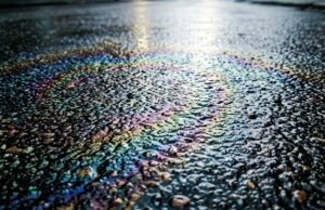 Perché i primi minuti di pioggia sono più pericolosi di un vero temporale Pellicola oleosa iridescente sull'asfalto bagnato nei primi minuti di pioggia dopo un periodo di siccità