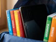 Il tablet nello zaino di scuola si rompe dall’interno: il gesto quotidiano che nessuno nota Tablet con schermo incrinato a ragnatela incastrato tra i libri scolastici colorati dentro uno zaino blu