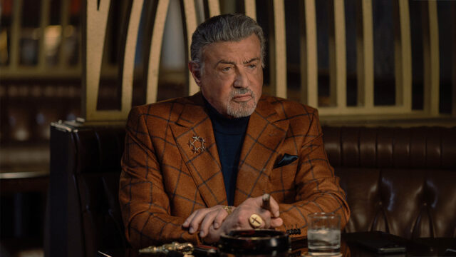 Sylvester Stallone nei panni di Dwight Manfredi, seduto al tavolo di un locale con un sigaro in mano, in una scena della quarta stagione di Tulsa King