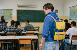 Lo zaino Invicta comprato a rate dai genitori: il vero motivo del suo successo Ragazzo con zaino Invicta giallo e blu anni '90 in un'aula scolastica