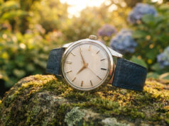 Tutti gli orologi del mondo girano nella stessa direzione, e la ragione non è un caso Orologio automatico vintage con cinturino blu su una pietra muschiata in un giardino al tramonto, quadrante bianco senza marchi visibili