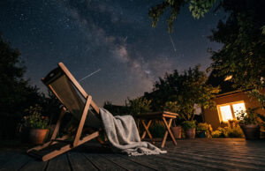 Stelle cadenti stanotte: il motivo per cui in tanti non ne vedranno nessuna Sdraio vuota con plaid su una terrazza di notte, sotto un cielo stellato con alcune scie di stelle cadenti visibili a occhio nudo