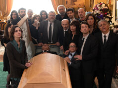 La nuova commedia di Massimiliano Bruno è al cinema da oggi, ma la storia non è affatto nuova Il cast di Un tranquillo funerale di famiglia riunito attorno alla bara durante una scena del film di Massimiliano Bruno